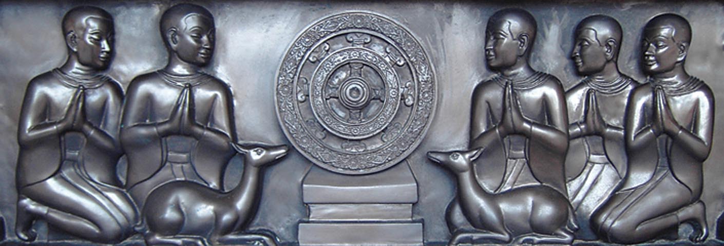 Les cinq compagnons du Bouddha durant sa période d’ascèse devinrent ses cinq premiers disciples. Ici, ils entourent une roue qui symbolise le Bouddha et ses enseignements, dont les premiers furent donnés au Parc des gazelles à Sarnath. Photo de DhJ.