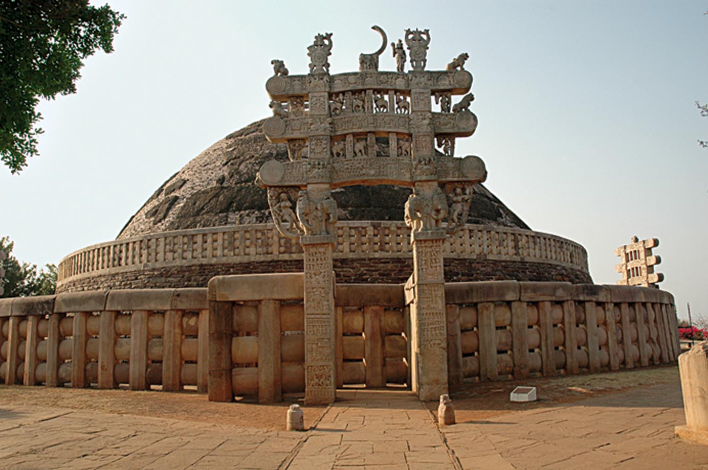 Le grand stoupa de Sāñcī, situé dans l’actuel Madhya Pradesh, fut commandé par l’Empereur Aśoka et l’on pense qu’il contient une des reliques originales du Bouddha Sākyamuni. Le stoupa garde également vivante la présence du Bouddha grâce aux sculptures qui représentent les événements de sa vie. Photo de Marc Shandro.